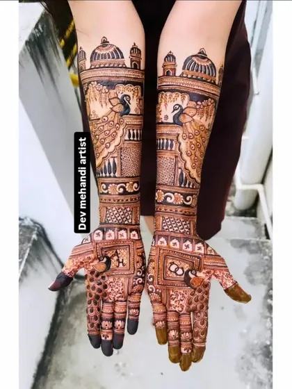 A beautiful design featuring peacocks looking out from palace windows (jharokhas). This style of architectural mehndi adds a royal and narrative element to your bridal look.