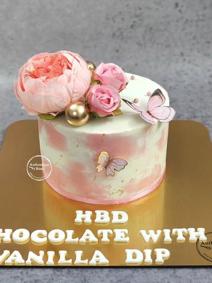 A close-up of our butterfly floral cake, showing the detail of the handcrafted flowers and gold accents. This one is a chocolate with vanilla dip flavor.