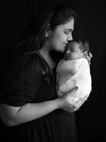 Sometimes, stripping away the color reveals the true emotion of a moment. This black and white portrait of a mother's gentle kiss on her sleeping newborn's forehead is all about the feeling, the connection, and the quiet love.