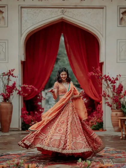 A happy bride twirling in her beautiful lehenga, with the rich red drapes and floral decor creating a stunning frame.