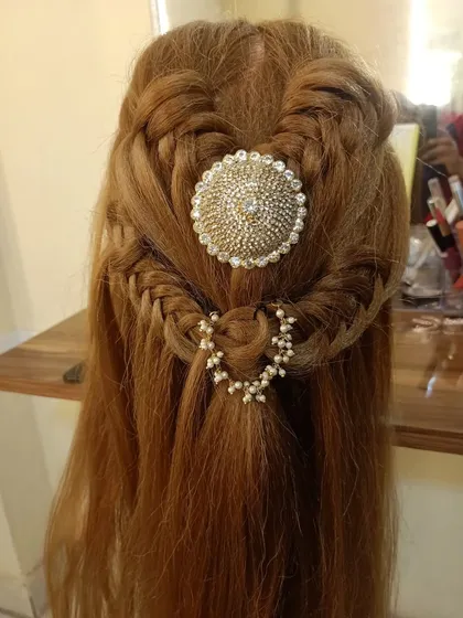 A half-up hairstyle with intricate braids and a statement hair accessory.