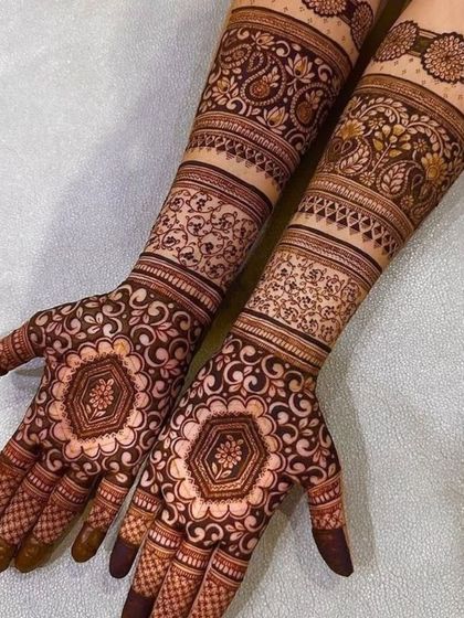 This design features hexagonal mandalas on the palms, surrounded by delicate vine patterns and detailed bands on the arms.