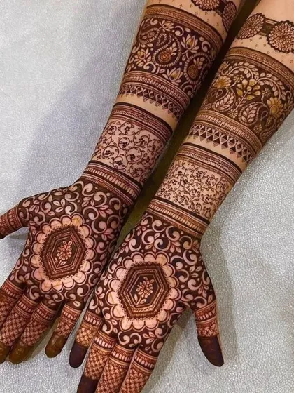 This design features hexagonal mandalas on the palms, surrounded by delicate vine patterns and detailed bands on the arms.