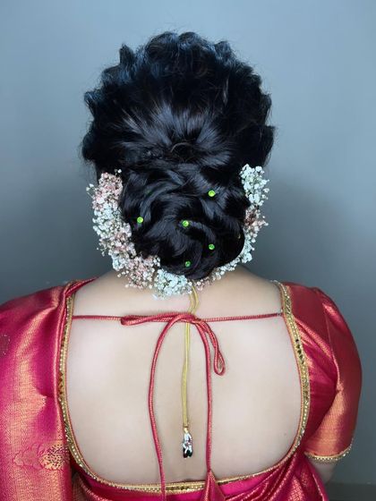 A full view of the simple twisted bun, showing how the baby's breath creates a soft, cloud-like effect around the hairstyle. It's a romantic and modern choice for any pre-wedding celebration.