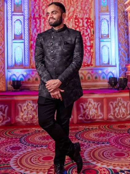 A classic Jodhpuri, or bandhgala, suit in a dark, self-patterned fabric. Paired with tailored trousers, this is a timeless and formal option for any wedding event.