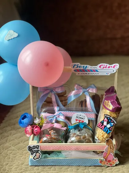 A perfect hamper for a gender reveal party. I use pink and blue themes with balloons and fun stickers to build excitement, packing the crate with delicious cookies and snacks for everyone to enjoy during the celebration.