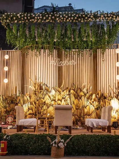 A modern and chic open mandap design. I used a curved, slatted wooden backdrop, dried palm leaves, and fresh white florals to create a boho-luxe setting that is both stylish and serene.