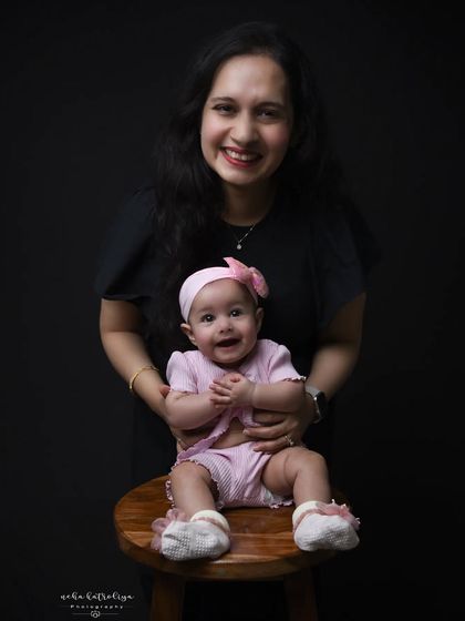 A beautiful mother-daughter portrait. The dark background makes their bright smiles pop, creating a classic and timeless image that highlights their special connection.