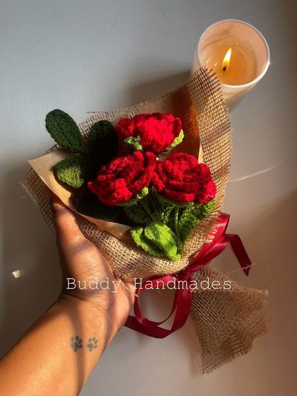A classic red rose bouquet, held in hand to show its size and detail. The candle in the background adds a touch of warmth, highlighting the romantic feel of these forever flowers.