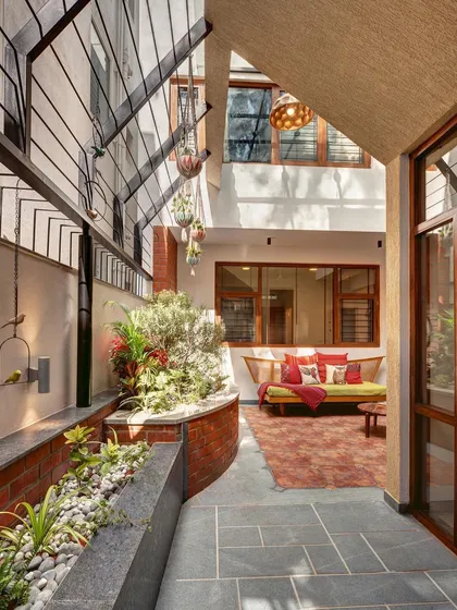 An internal courtyard that acts as the home's sanctum. The design uses brick planters, slate flooring, and open-to-sky elements to create a peaceful, green oasis that brings nature right into the heart of the house.