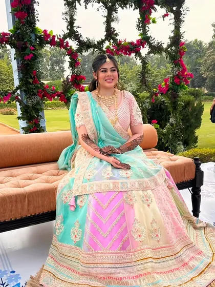 Another shot of the bride, this time seated, giving a full view of her gorgeous lehenga and the detailed mehndi on her hands.