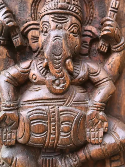 A close-up of one of the figures from the 4-foot Ashta Ganesha vertical panel. This detailed shot reveals the texture of the wood and the expressive character captured in the carving.