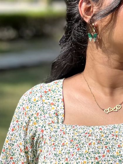 A close-up on the accessories for this look. The delicate heart necklace and butterfly earrings add a touch of whimsy to the floral dress.