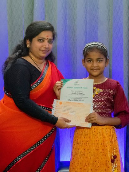 A young student in traditional attire receives her music exam certificate.