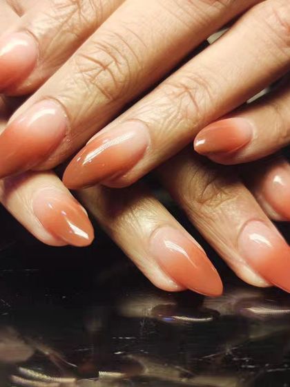A warm and earthy ombre design, blending from a sheer nude to a burnt orange shade.