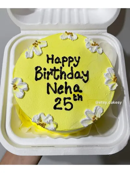 A cheerful yellow bento cake for Neha's 25th birthday, decorated with small white flowers.