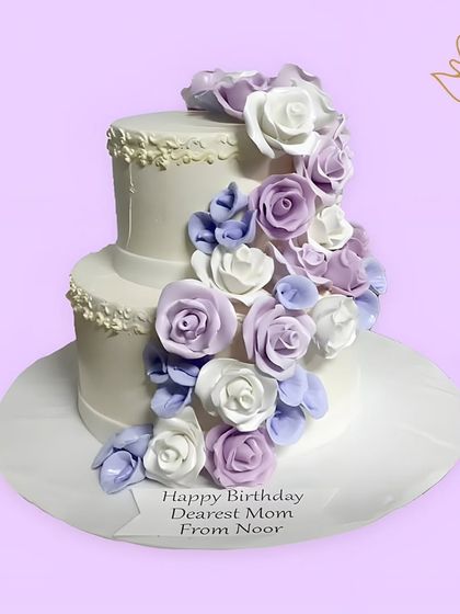 A beautiful two-tier floral cake for a mother's birthday. This design features a cascade of purple and white sugar roses, creating a truly stunning and heartfelt gift.