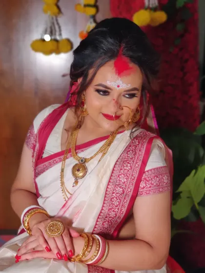 The classic white and red Bengali saree paired with gold jewellery is a timeless combination.