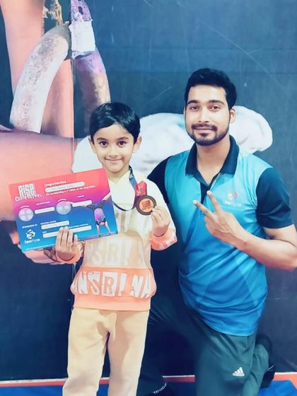 A happy gymnast shows off her medal and certificate with her coach.