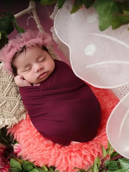 A close-up of the sleeping baby in the butterfly-themed setup. This angle highlights the delicate floral headband and the peaceful expression of the baby.