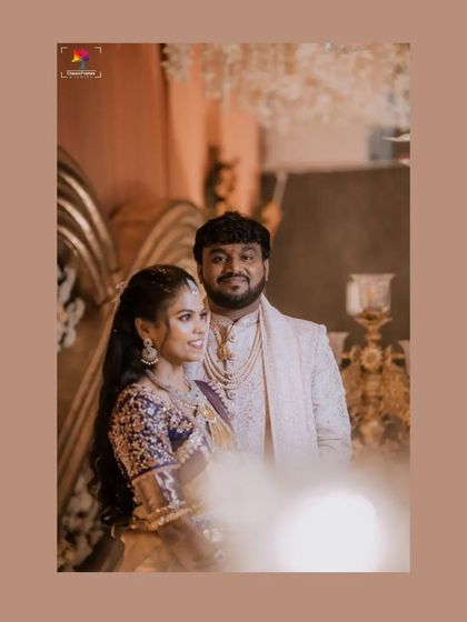 A candid reception portrait where the couple shares a happy moment. The warm lighting and floral background add to the celebratory and romantic mood.