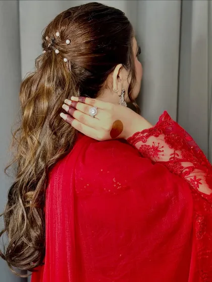 The back view of the elegant ponytail, showing the detail of the pearl hairpins and the soft waves.