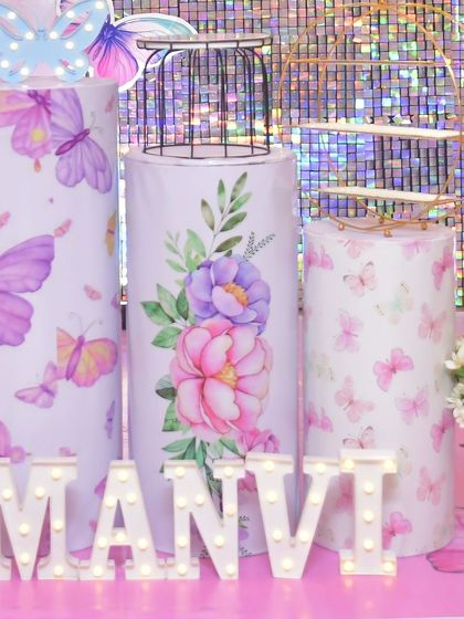 Custom-designed pedestals and light-up marquee letters for Manvi's butterfly-themed party. The plinths are wrapped in beautiful floral and butterfly patterns to perfectly match the event's aesthetic.