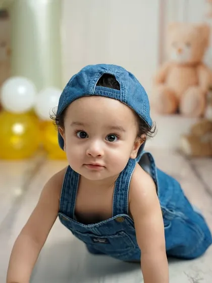 A close-up shot capturing the curious and sweet expression of the birthday boy as he crawls towards the camera during his denim-themed session.