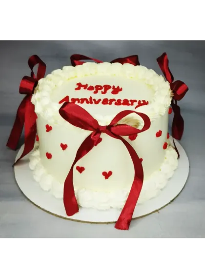 A classic anniversary cake with a vintage touch. This basic vanilla cake is decorated with delicate piping and beautiful red satin bows.