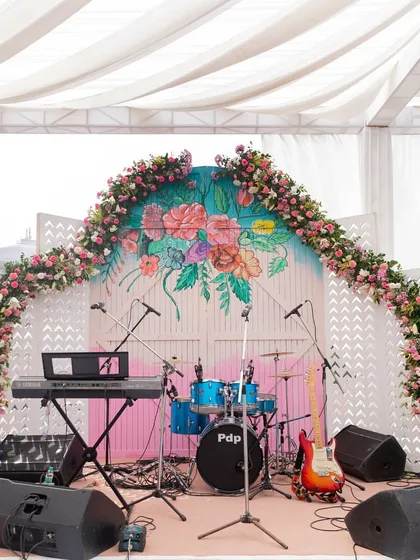 The stage for a live band, decorated with a hand-painted floral backdrop and a matching floral arch.