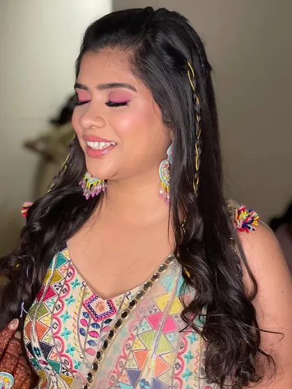 A fun and colorful Haldi look. The bride's multi-colored outfit was paired with a bright pink eyeshadow and a playful hairstyle. 🧡💛💚💜