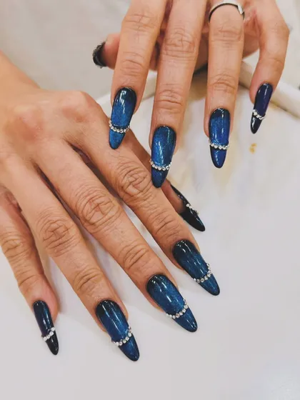 For those who love a dramatic flair, we created this stiletto nail set featuring a deep blue cat-eye effect. To elevate the look, we added a delicate band of shimmering rhinestones, making each nail a piece of jewelry.