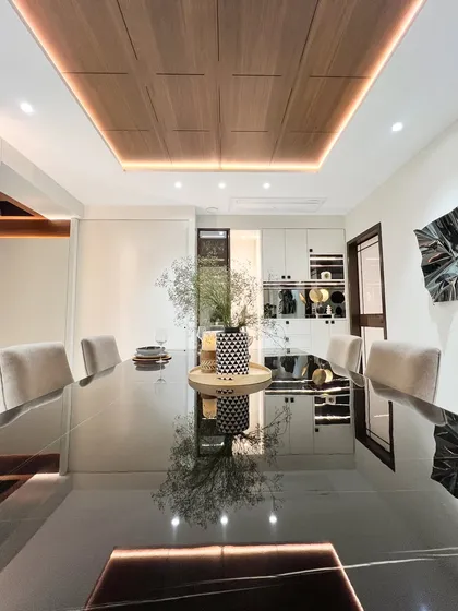 Another view of the dining table, this time capturing the reflection of the centerpiece and the distant kitchen. This shot highlights the seamless, open-plan nature of the space we designed.