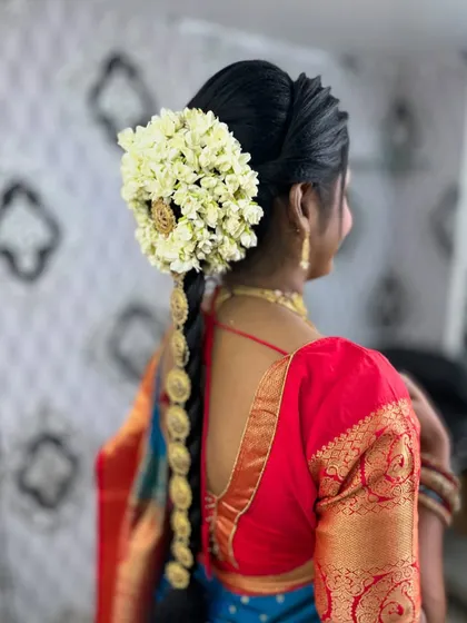 A traditional South Indian bridal hairstyle featuring a long braid decorated with flowers and golden accessories.