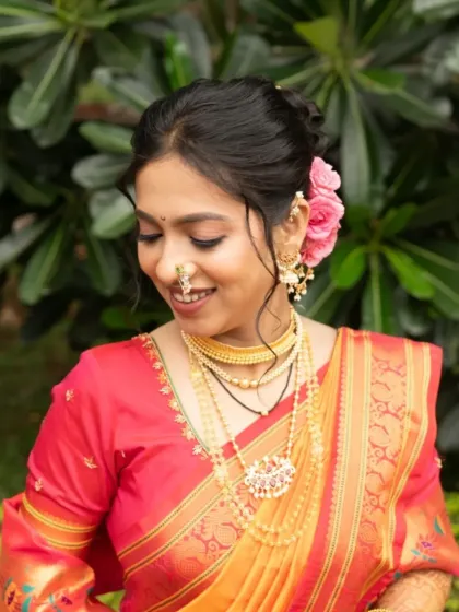 A close-up portrait showing the soft makeup and the traditional gold jewellery that completes the look.