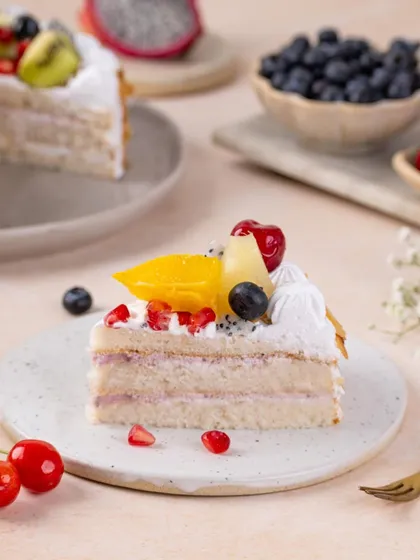 A perfect slice of fresh fruit cake. The styling is clean and simple, letting the vibrant colours of the fruit and the light, airy sponge be the stars of the show.