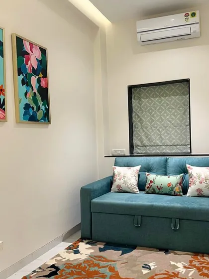 A cozy den in the South Mumbai residence, where a teal sofa bed is paired with vibrant floral artwork and a colorful rug. This multi-functional space is designed to be both stylish and practical.