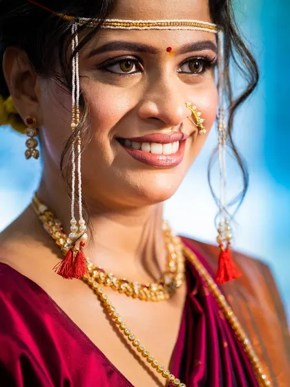 A beautiful close-up showcasing her smile and the intricate details of the *mundavalya*. The makeup is natural, with a focus on flawless skin and bright eyes.