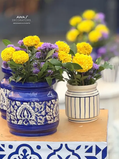 A close-up of the floral arrangements, featuring yellow marigolds and purple statice in beautifully detailed blue and white ceramic jars.
