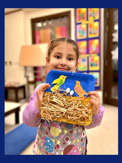 Look at that proud smile! This little artist is showing off her mixed-media bird's nest, a fun sensory project that helps toddlers explore textures and build motor skills.