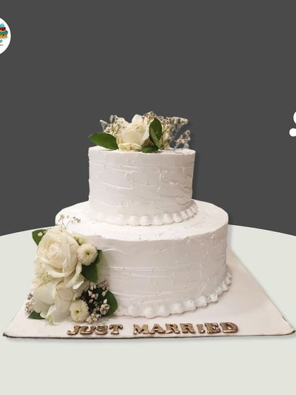 Another beautiful "Just Married" cake, this design features two tiers of rustic textured white buttercream and is decorated with clusters of fresh white roses and baby's breath.