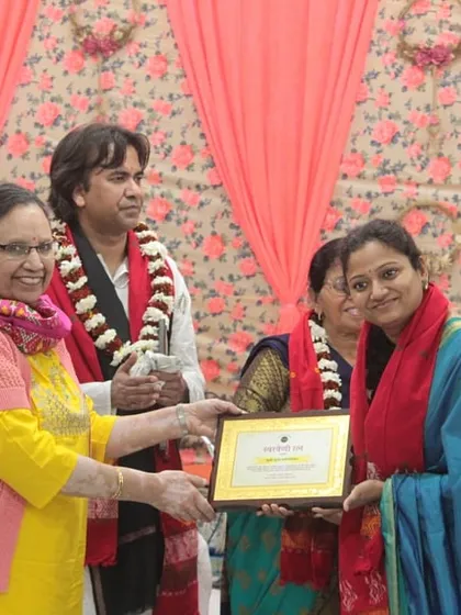 A female artist being felicitated on stage, a moment of recognition and encouragement.
