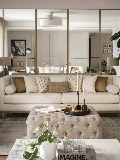 The combination of the tufted ottoman, marble coffee table, and layered sofas creates a rich, multi-textured living space.