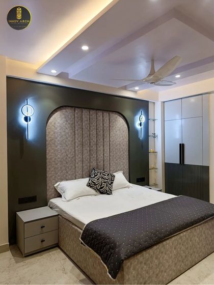 Another view of the son's bedroom, focusing on the custom bed with an upholstered, arched headboard. The modern wall sconces and two-tone wardrobe add a touch of contemporary elegance to the room.
