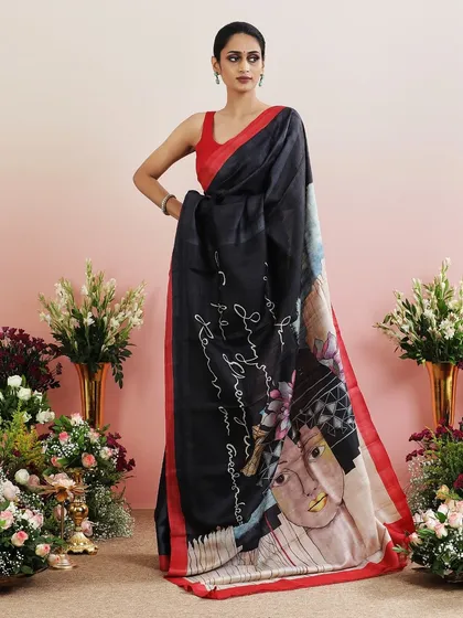 A black saree with an abstract face and floral print on the pallu, a piece of wearable art.