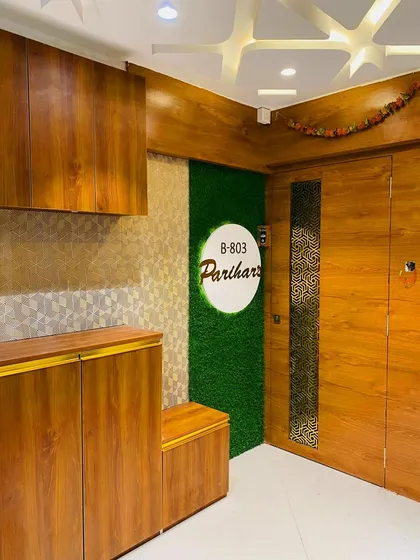 We designed this entrance for the Parihar family with a mix of textures. The design includes a main door with a jali insert, a shoe rack, and a green artificial grass panel for the nameplate.