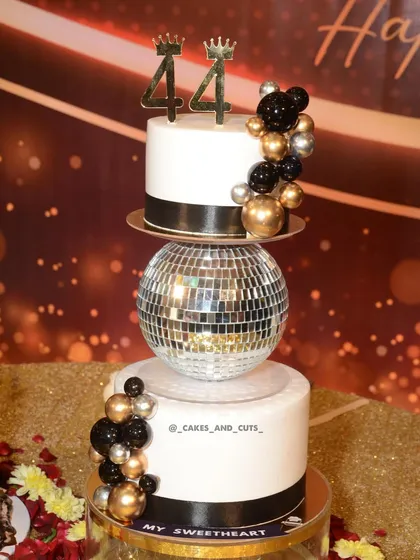 A close-up of the 44th birthday cake, showing the number toppers and the metallic balloon decorations.
