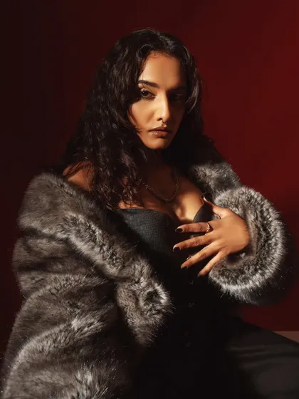 The same setup, but in color with a deep red background. The warm light hitting the model creates a rich, sensual mood, contrasting with the cool tones of the fur.