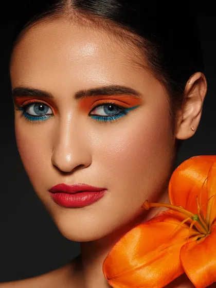 A bold and contrasting look with bright orange eyeshadow and a teal liner, perfectly matching the vibrant orange lily.