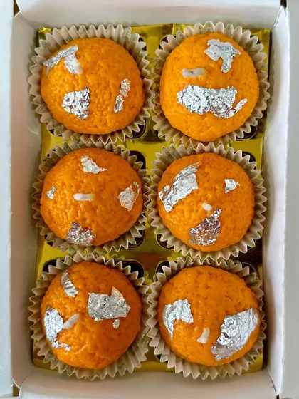A top-down view of a box of six Laddoo candles, showing their realistic texture and silver leaf detailing.